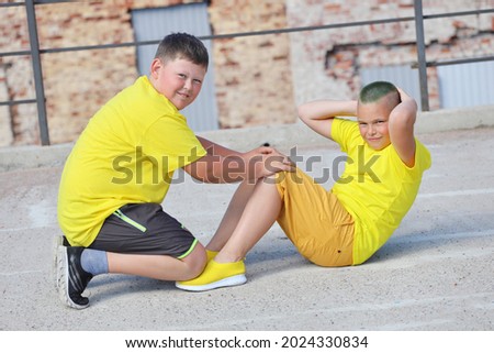 two young boys in yellow T-shirts are training. Training of abdominal muscles. High quality photo