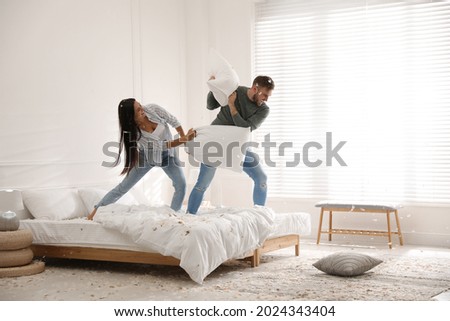 Happy young couple having fun pillow fight in bedroom Royalty-Free Stock Photo #2024343404