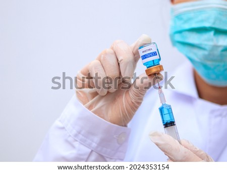 Close up on Vaccine, Asian doctor, scientist, wearing gloves, holding Vaccine, syringe, concept, a virologist who invented the vaccine against COVID-19. part of the global coronavirus vaccine pandemic