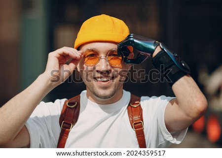 Young disabled man portrait put on yellow glasses with artificial prosthetic bionic robotic hand Royalty-Free Stock Photo #2024359517