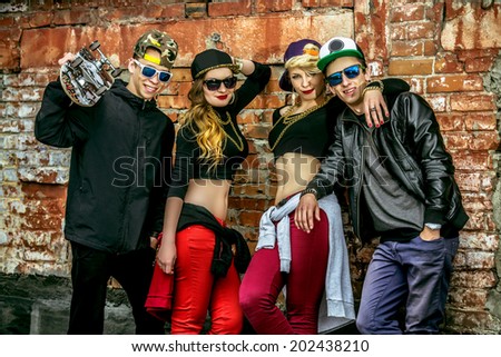 Group of young modern people posing together with fun. Urban lifestyle. Hip-hop generation.