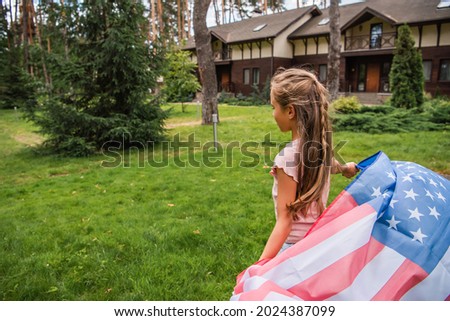 Girl holding american flag on lawn outdoors