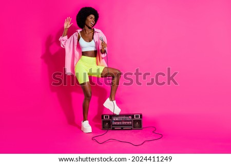 Photo of cute funky dark skin woman dressed crop top smiling listening boombox singing empty space isolated pink color background