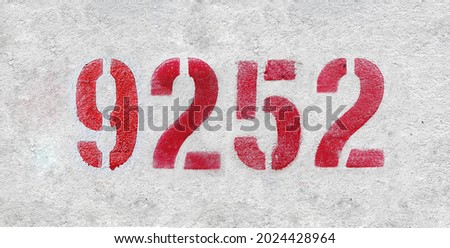 Red Number 9252 on the white wall. Spray paint. Number nine thousand two hundred fifty two.