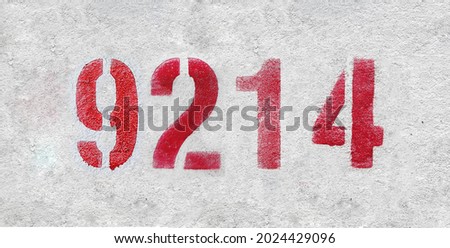 Red Number 9214 on the white wall. Spray paint. Number nine thousand two hundred and fourteen.