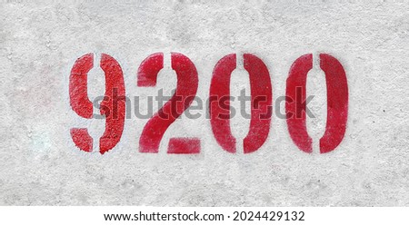 Red Number 9200 on the white wall. Spray paint. Number nine thousand two hundred.