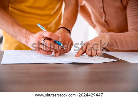 Cut out midsection image hands signing documents. Female helping Male to sign the papers of bank deal. Closeup selective focus