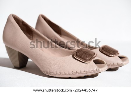a pair of female shoe made of natural leather. hand made beige medium heel shoes decorated with wooden element. women's shoes concept. leather high quality and exclusive footwear.