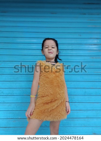 Portrait of cute little Indian girl posing against wall
