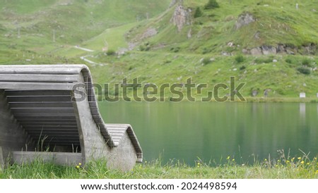 A beautiful view of the rocky green mountains with the water and a bench