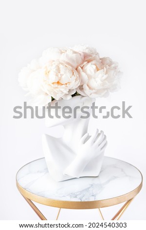 Fresh bunch of white peonies in vase in shape of womens face on light background. Trendy Ceramic Vase of human head, Handmade Modern Statue Art Flower Vase. Card Concept, copy space for text Royalty-Free Stock Photo #2024540303