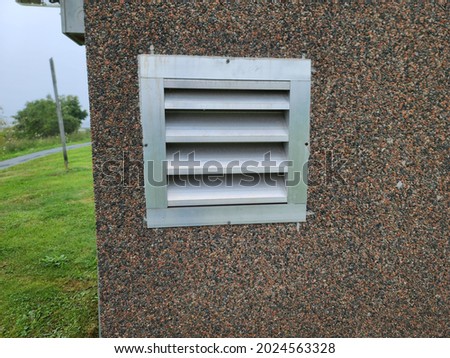An air vent in the exterior of a suburban home. The vent has several slats for air to pass through. It's in the cement foundation of the house. Royalty-Free Stock Photo #2024563328