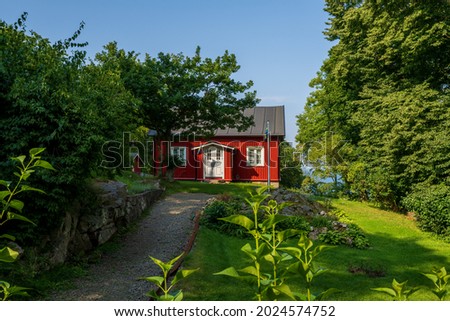 Typical red wooden cottage in Sweden with beautiful garden and a flagpole. Royalty-Free Stock Photo #2024574752