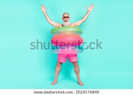 Photo of crazy old man enjoy fun raise hands wear lifebuoy sunglass shorts isolated turquoise color background