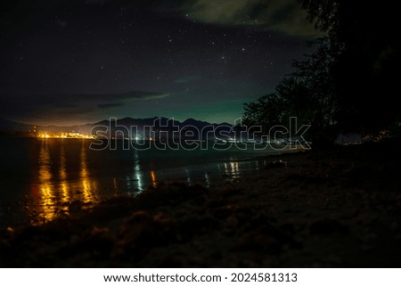 A seashore at night and colorful lights of the town on the other side