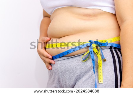 Beautiful fat woman with tape measure She uses her hand to squeeze the excess fat that is isolated on a white background. She wants to lose weight, the concept of surgery and break down fat  Royalty-Free Stock Photo #2024584088
