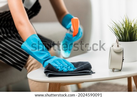 Close up, Housekeeper wearing protective gloves cleaning table using alcohol and liquid cleaning solution to prevent coronavirus (COVID-19) infection, Disinfection and Hygiene home concept. Royalty-Free Stock Photo #2024590091