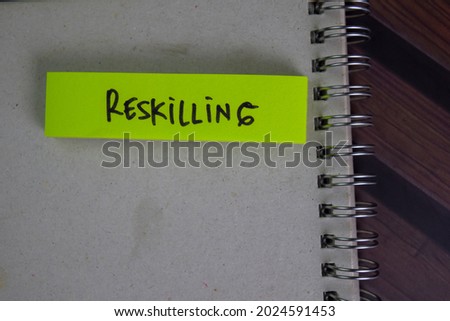 Reskilling write on sticky notes isolated on Wooden Table.