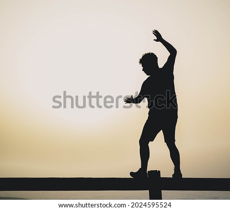 A silhouette of a man posing with sunset view in the background