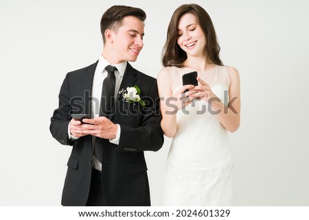 Look at this picture. Cheerful bride-to-be showing a text on the smartphone to her happy groom 