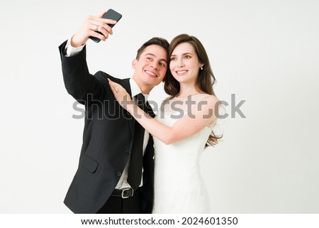 We got married. Caucasian couple taking a selfie together. Bride and groom posting a picture on social media at her wedding day