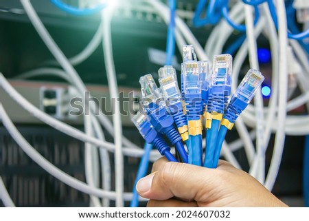 Close-up hand choose many RJ45 head of UTP LAN network cable and Lots of Ethernet cables background for connect computer and network devices to switch or hub modem router in cabinet. Royalty-Free Stock Photo #2024607032