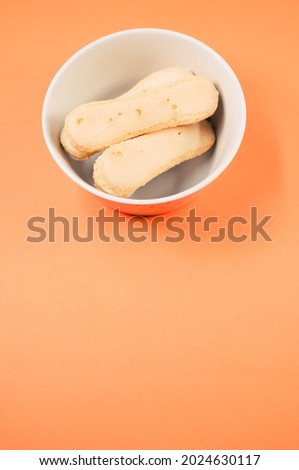 A vertical shot of ladyfinger cookies on a bowl isolated on yellow background
