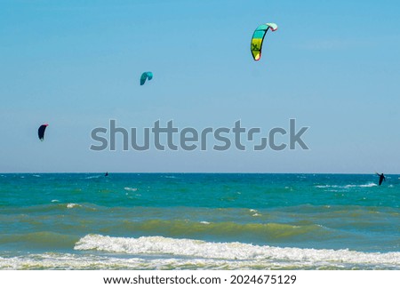 Three kitesurfers enjoying the surf on the sea