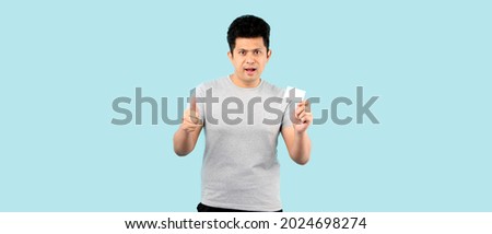 Asian man holding credit card on a blue background.