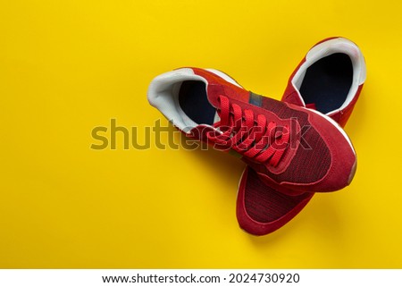 Pair of new red sneakers on a yellow background. Casual shoes. Space for text. Top view.
