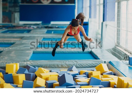 Young and beautiful woman plays in dry pool with cubes.