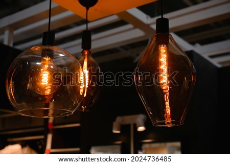 Three glowing vintage light bulbs of different shapes. Fashionable modern round lamp in retro style hanging from ceiling, decor for indoor home interior. Selective focus