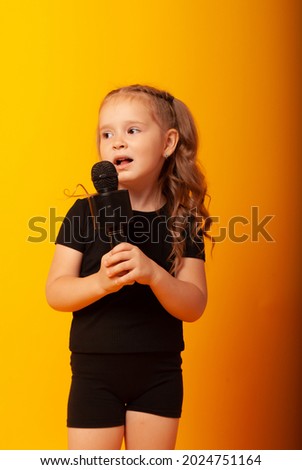 girl singer on a yellow background with a microphone in her hands is learning to sing. Vocal lesson at school