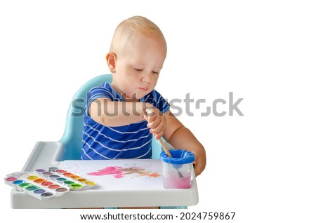Happy cheerful child drawing with brush in album using a lot of painting tools. Creativity concept. Isolated