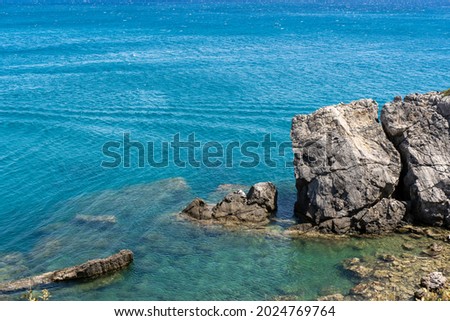 Cliffs rising from the clear blue and turquoise sea water of Preveli Beach in Crete, Greece. The beautiful calm water of the Mediterranean Sea