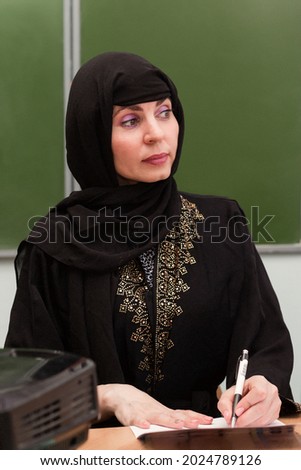 Muslim girl teacher working with school documents.,
