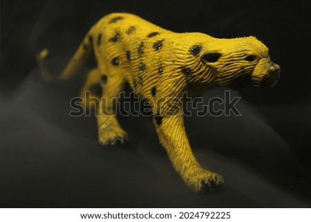 used toy yellow tiger on black background and smoke
