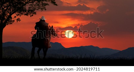 silhouette cowboy horseback riding transportation at sunset time with mountaind and sun sky background.