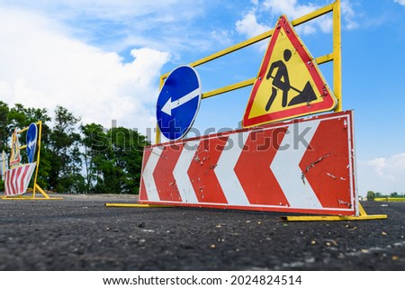 Road works sign on the road. Repair work of road signs and a bypass arrow on a background of blue sky.