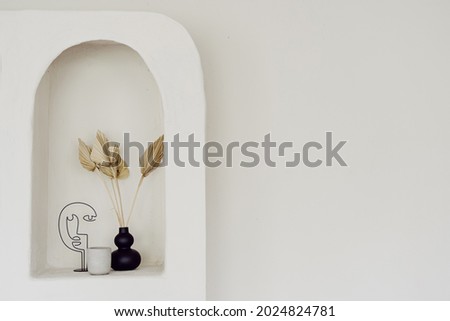 Wall decor at interior design, white arch niche. Vintage style decoration of living room, cope space. Stylish indoor minimal decor. Ceramic vase with dry plant, retro home furniture. Royalty-Free Stock Photo #2024824781