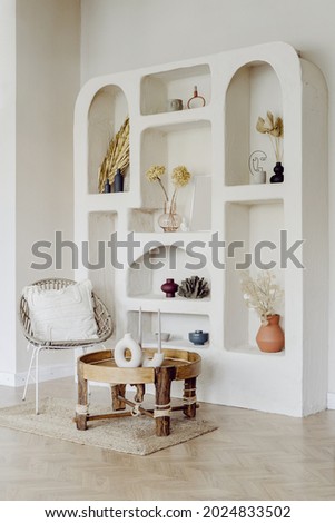 Interior design with white wall in living room. Modern decor for house, vertical shot of style in modern apartment, wicker chair near wooden table. Cozy decoration at niches.