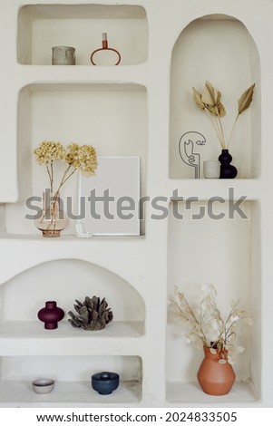 Vertical shot of wall decor, white shelves in apartment interior. Vintage decoration for home indoors, close up of niches in scandinavian room. Natural decor with dry plants in vase.