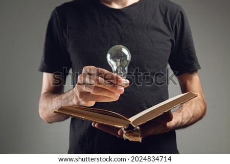 man holding an open book and a light bulb. concept idea from a book