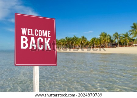 A welcome back sign in front of a tropical beach resort, welcoming back tourists after closure, rehabilitation or travel ban.