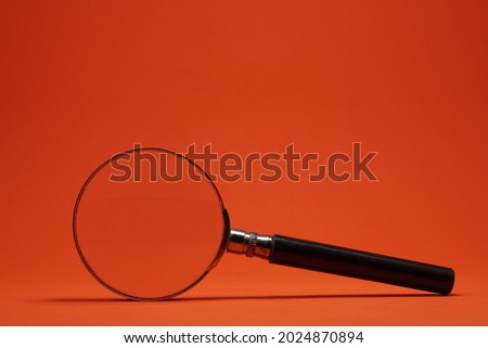 Reading loupe is a tool to zooming text when reading book. Reading loupe or magnifying glass on isolated orange background.  Royalty-Free Stock Photo #2024870894