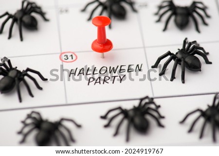 Above photo of label date 31 october with inscription halloween party red pin and pile of spiders isolated on the calendar background