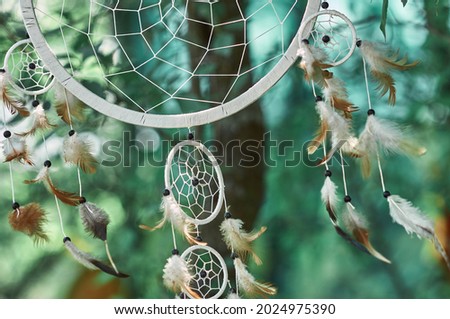 Photo of a dream catcher. Home decoration is made of wooden round hoops, white threads, beads and feathers. this item is usually hung over the bed. It takes bad dreams away from their master.