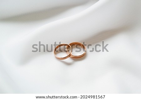 Gold wedding rings on white cloth. Close-up.