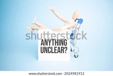 Wooden Doll in a shopping with white paper and ANYTHING UNCLEAR sign. Business concept