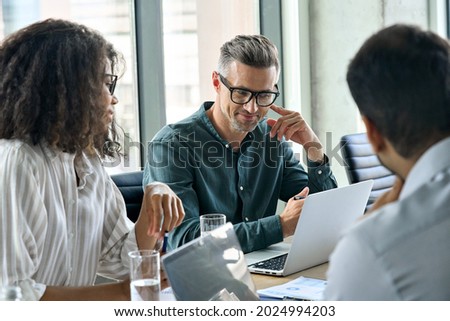 Diverse international executive business people working on project at boardroom meeting table using laptop computers. Multiracial team discussing project strategy working together in modern office. Royalty-Free Stock Photo #2024994203
